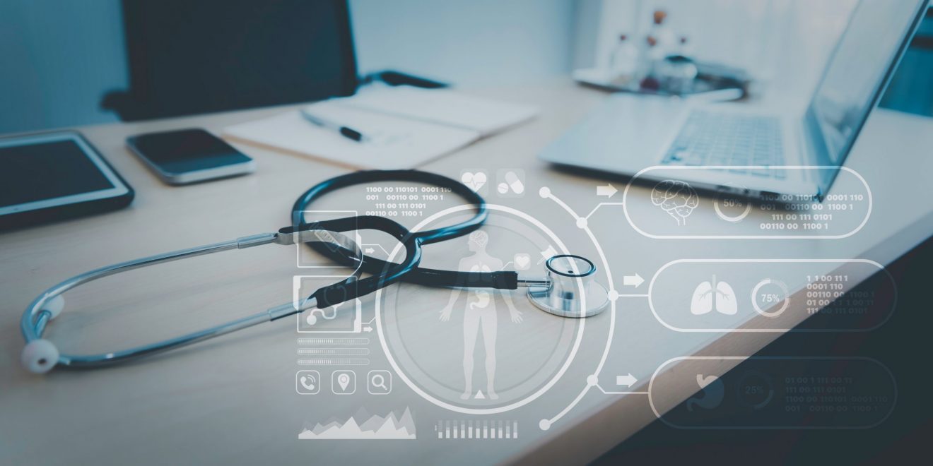 A stethoscope resting on a desk next to a laptop and a smartphone; an illustration of modern healthcare technology.