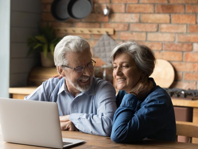 An elderly couple seated at a table, using a laptop to view AI-driven dietary recommendations.