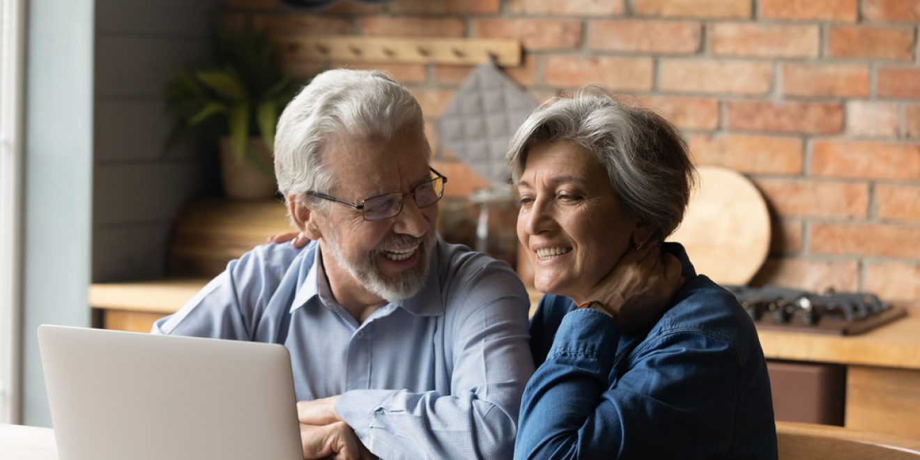 An elderly couple seated at a table, using a laptop to view AI-driven dietary recommendations.