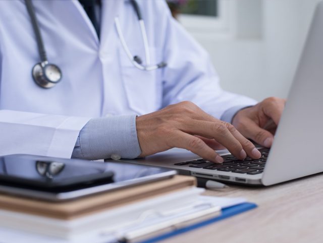 Doctor using a laptop to input medical information.