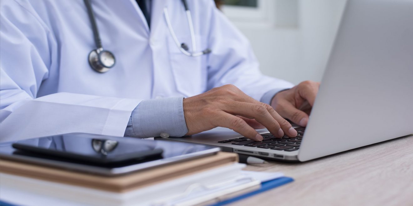 Doctor using a laptop to input medical information.