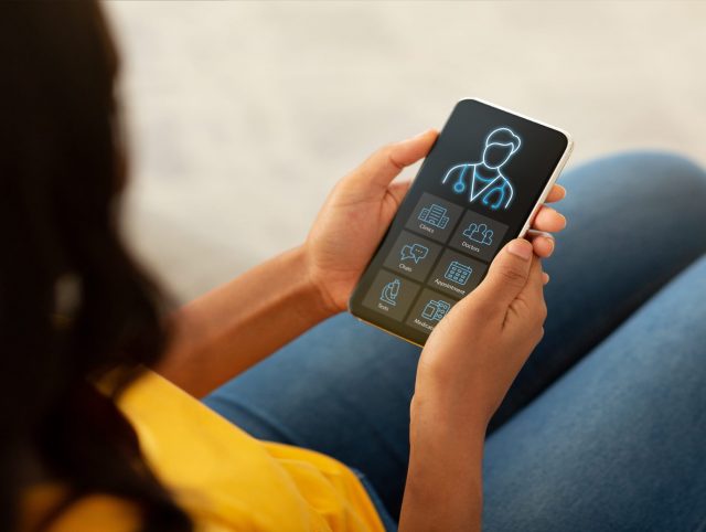 Woman holding a smartphone displaying a healthcare mobile app interface.