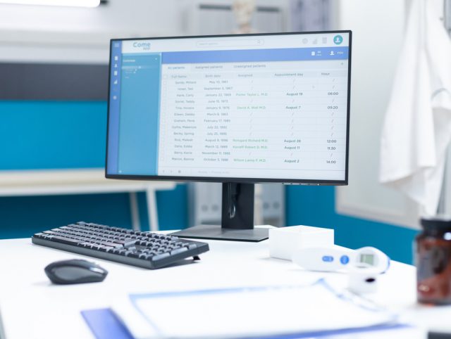 A desk with a computer monitor, keyboard, and mouse in a doctor's office, showcasing product development technologies in healthcare.