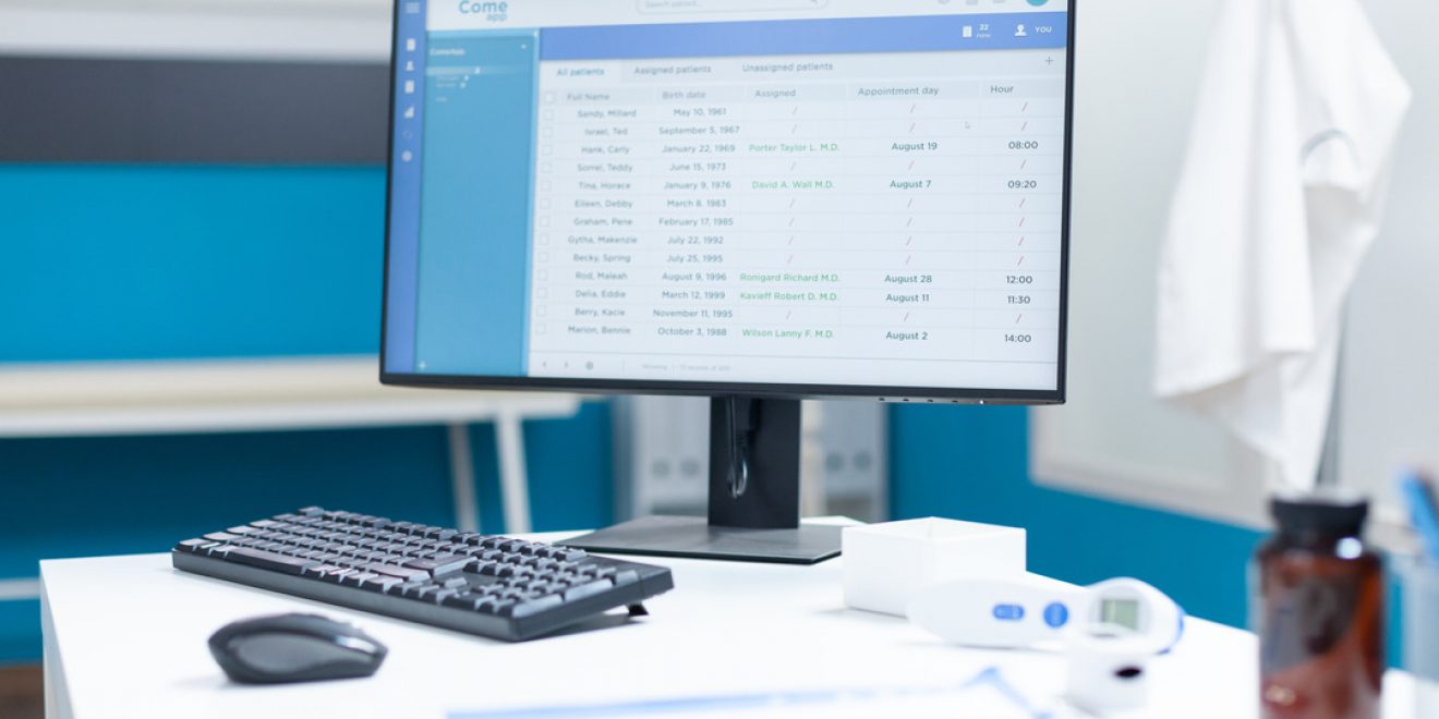 A desk with a computer monitor, keyboard, and mouse in a doctor's office, showcasing product development technologies in healthcare.
